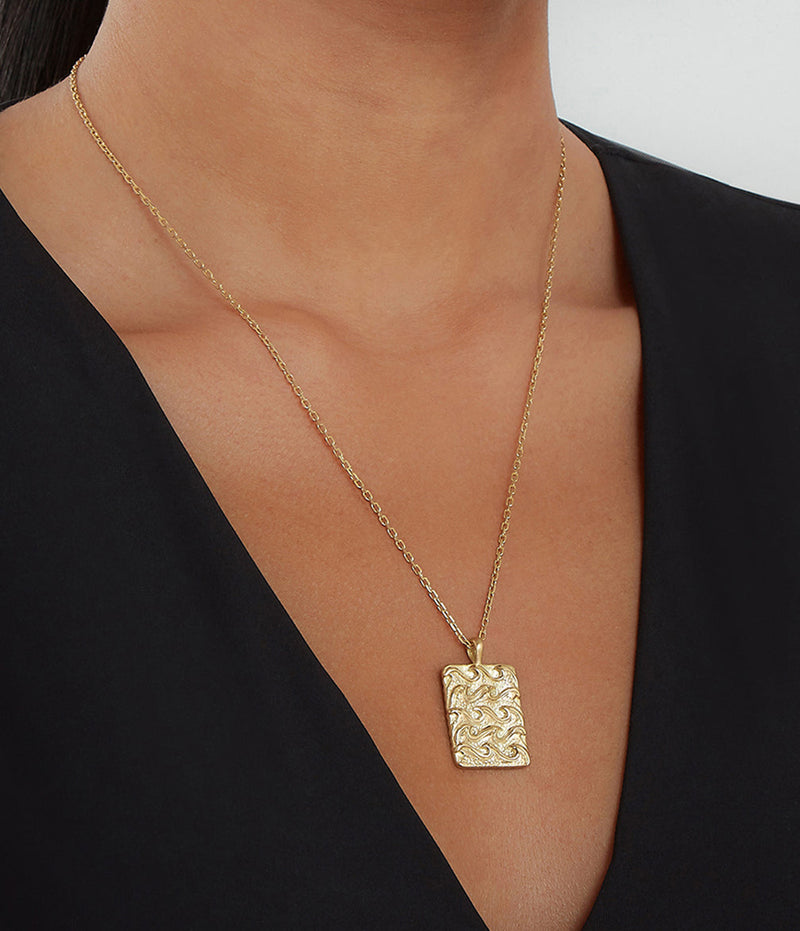 Aquarius zodiac pendant gold necklace worn with a black v-neckline shirt